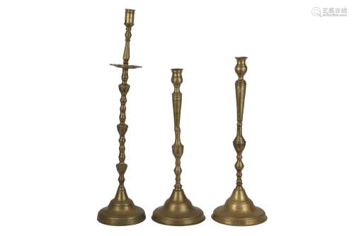 A NEAR PAIR OF BRASS CANDLESTICKS AND AN INDIVIDUAL TALL CAN...