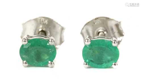 A pair of white gold single stone emerald stud earrings,