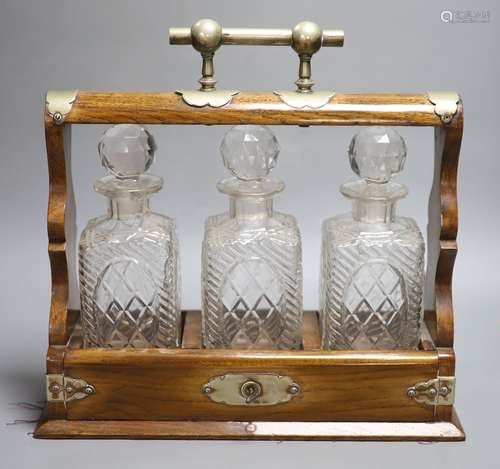 An oak three decanter tantalus, with key