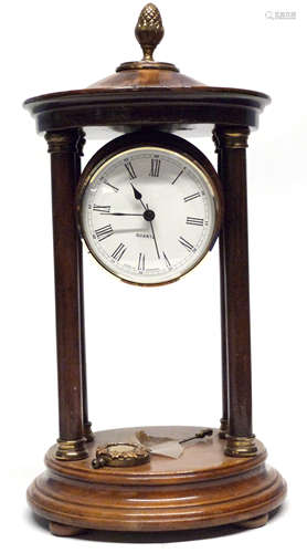 Quartz clock in wooden case, supported by four wooden pillar...