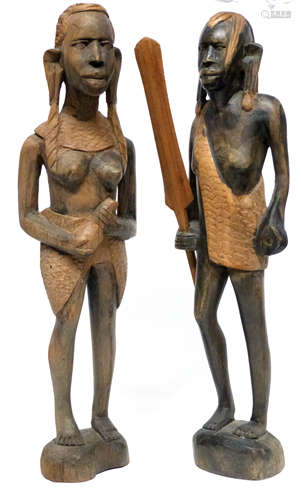 Pair of African carvings, one of a warrior holding a paddle,...