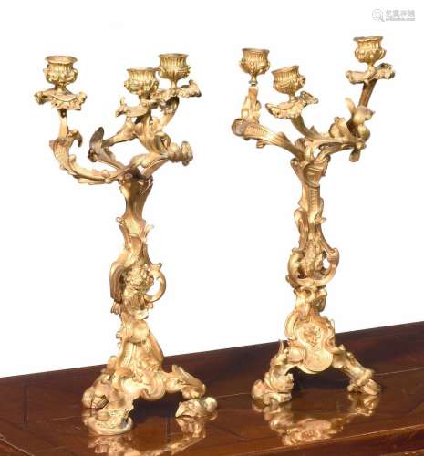 一对鎏金铜制烛台，有三个卷轴灯和镂空的叶子、花朵和贝壳装饰，背面...