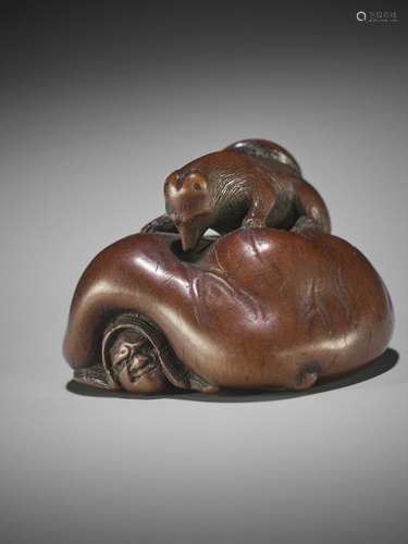 KIGYOKU: A WOOD NETSUKE OF A TANUKI CRUSHING A HUNTER