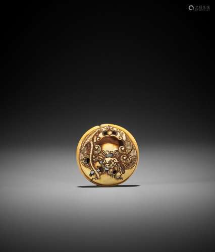 A STAINED IVORY RYUSA MANJU NETSUKE WITH A SHISHI EMERGING F...