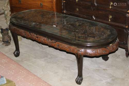 A Chinese hardwood oval coffee table deeply carved to top wi...