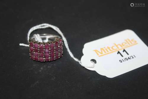 A silver and ruby ring, set with seven vertical rows of four...