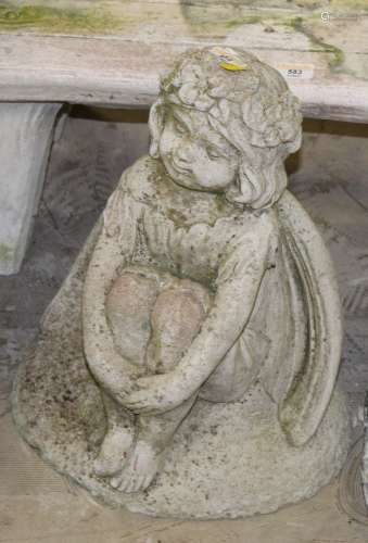 A cast composite stone garden statue of a seated angel,