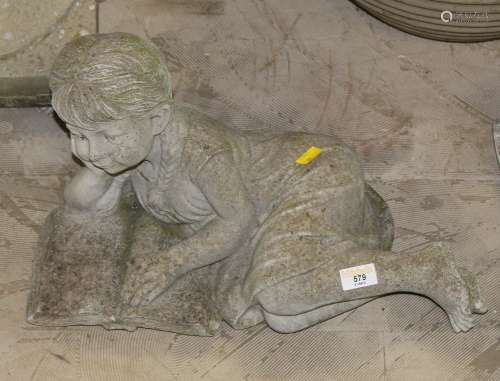 A cast composite stone garden statue of a reclining girl rea...