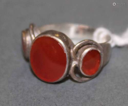 A silver and carnelian three stone ring, the central oval st...