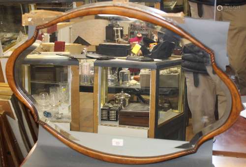 An early 20th century walnut bevelled mirror, of shaped oval...