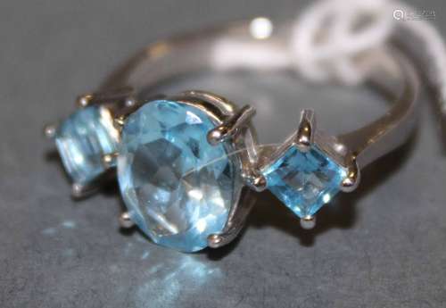 A silver and blue topaz three stone ring, the oval central s...