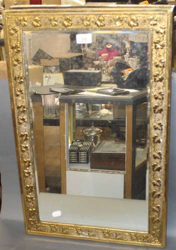 An embossed brass framed rectangular bevelled wall mirror,