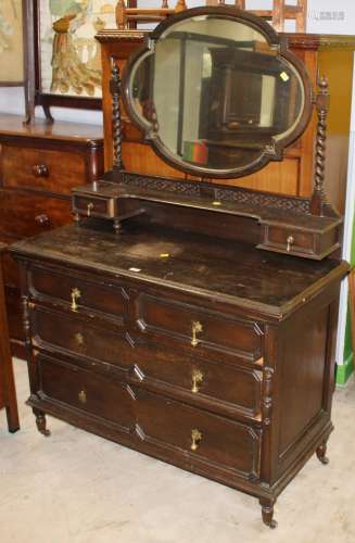 A 1920's dark oak dressing chest with oval mirror, spiral tu...