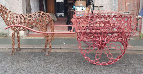 A red painted and welded metal horse and cart garden feature...