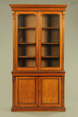 A late Victorian walnut glazed bookcase on cupboard,