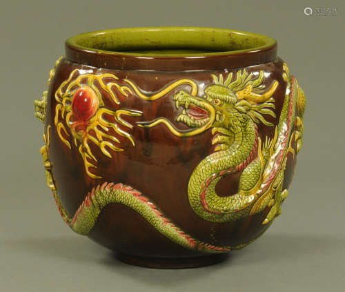 A large Bretby jardiniere, moulded with chasing dragons and ...