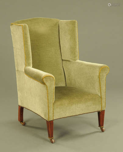 An Edwardian mahogany wing chair, upholstered in green velve...