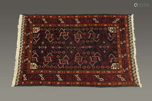 A Turkish hand woven fringed rug, principal colours red,