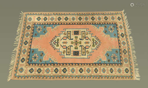 A Turkish woollen fringed rug, with centre rectangular panel...