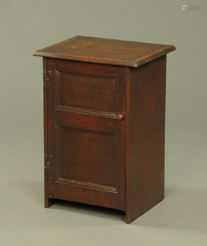 A mahogany bedside cabinet, with chamfered edge above a pane...