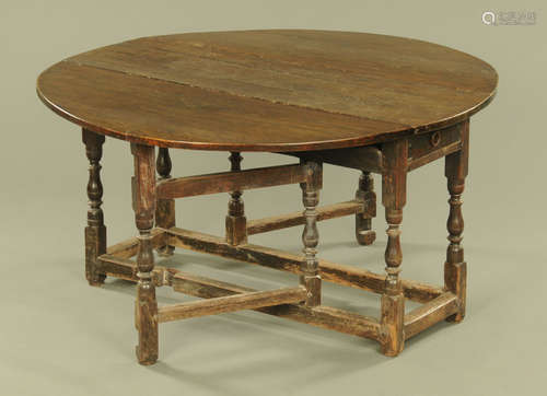 An antique oak gate legged dining table, with demi lune drop...