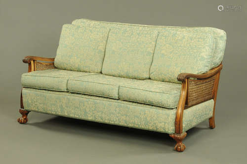 A walnut framed bergere lounge settee, with double caned sid...