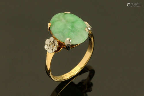 An 18 ct gold jade ring, with carved stone. Size L/M.