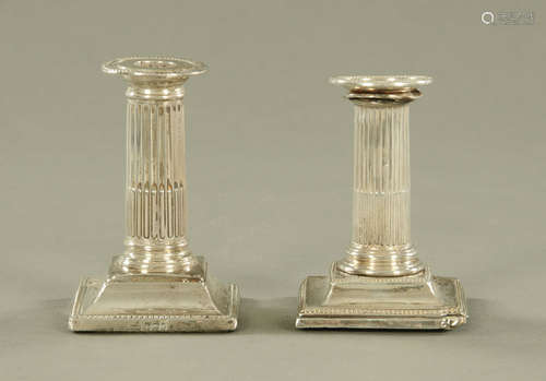 A near pair of silver candlesticks, with fluted columns and ...