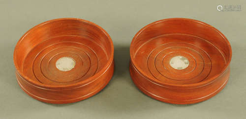 A matching pair of cherry wood and silver coasters.