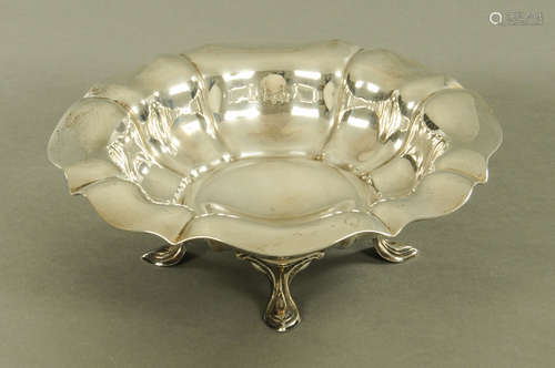 An Edwardian silver bowl, raised on four short cabriole legs...