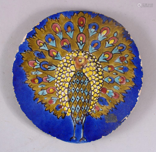 AN INDIAN CIRCULAR POTTERY TILE OF A PEACOCK, stood