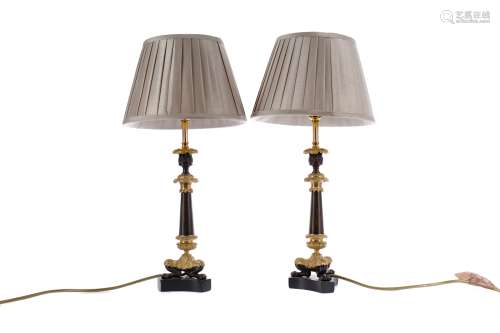 A PAIR OF REGENCY PATINATED AND GILDED BRONZE CANDLESTICKS C...