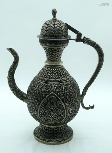 An Islamic white metal coffee pot heavily embossed with