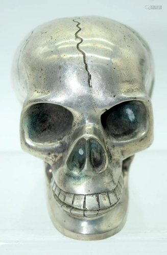 A small metal skull with a reticulated jaw.12 x 10cm .