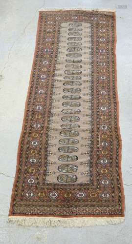巴基斯坦羊毛地毯，棕色背景上有几何装饰。230 x 77厘米。磨损。