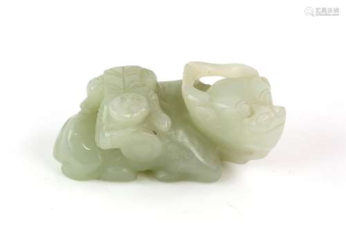 A small green jade carved as a boy climbing onto a recumbent...