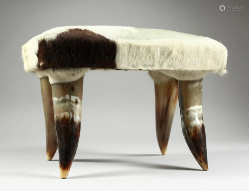 A SMALL HIDE STOOL on four horn legs, 1 ft. 2 in. high.
