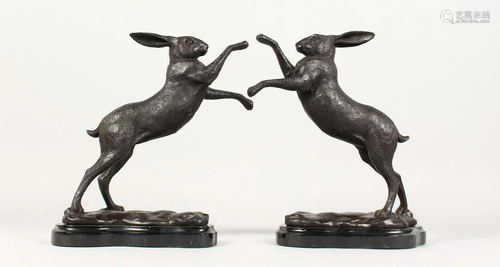 A PAIR OF BRONZE BOXING HARES on a shaped marble base