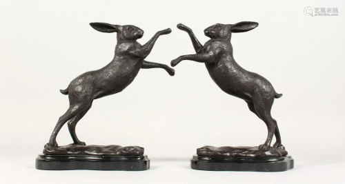 A PAIR OF BRONZE BOXING HARES on a shaped marble base