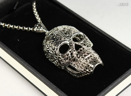 A SILVER SKULL PENDANT on a chain.