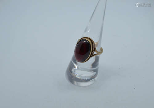 A 9ct gold garnet cabochon dress ring, oval stone in rope tw...