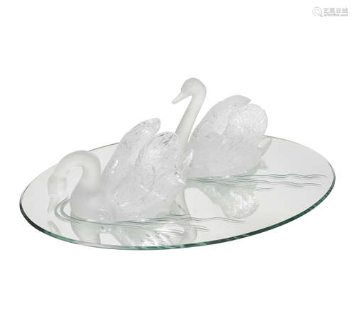 A PAIR OF LALIQUE CLEAR AND FROSTED GLASS SWANS ON AN OVAL M...