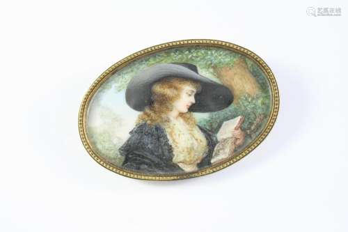 A PORTRAIT MINIATURE BROOCH depicting a young girl in a larg...