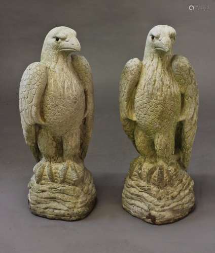 A PAIR OF RECONSTITUTED STONE FALCONS, each standing with wi...
