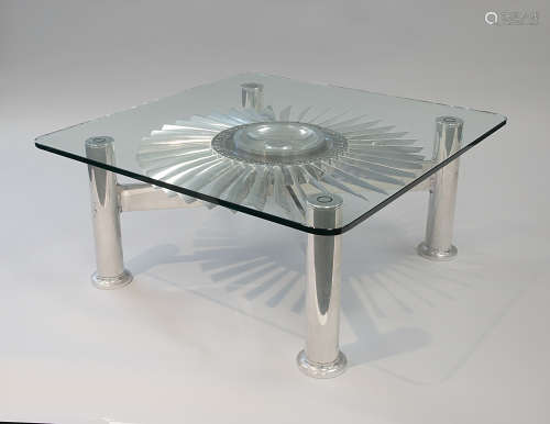 A MODERN STAINLESS STEEL AND GLASS TABLE FEATURING A JET ENG...