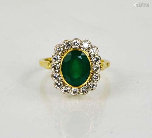 An 18ct gold, emerald and diamond ring, the oval cut emerald...