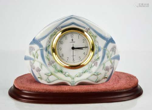 A Lladro porcelain clock with wooden stand, 13cm high.