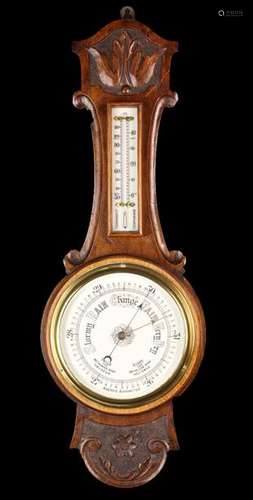 An Aneroid Barometer and thermometer on a wall mounted carve...