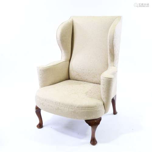 A 19th century upholstered wing armchair on walnut cabriole ...