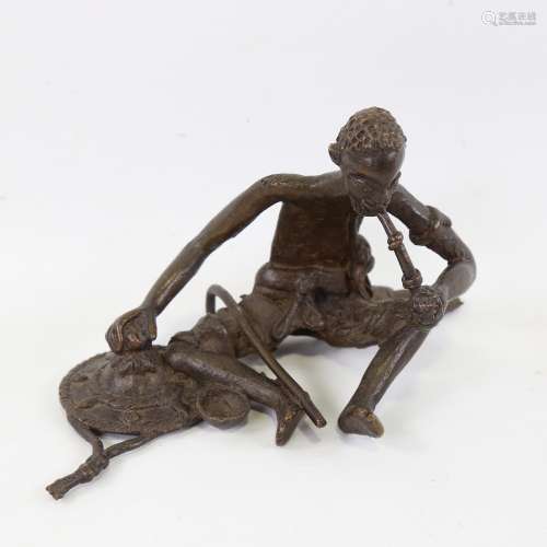 An African patinated bronze sculpture of a Tribesman smoking...
